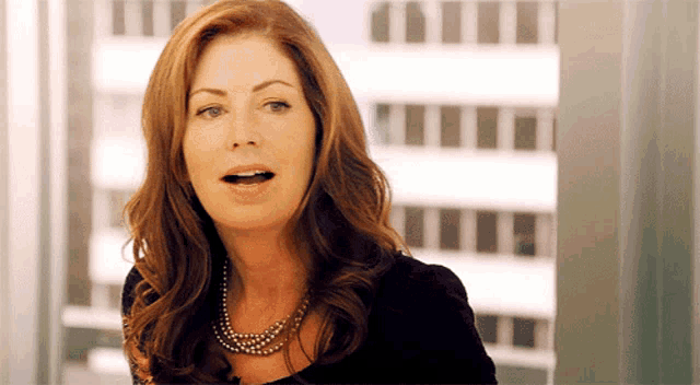 a woman wearing a pearl necklace and a black top