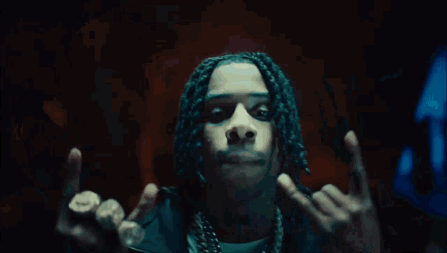 a close up of a man with dreadlocks making a peace sign