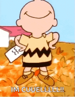 charlie brown is holding a piece of paper and smiling while standing in a field of pumpkins .
