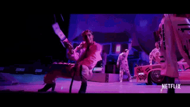 ariana grande is performing on stage with a group of dancers in purple outfits .