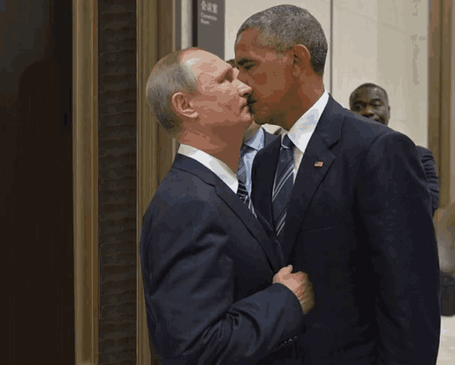a man in a suit and tie kisses another man in a suit