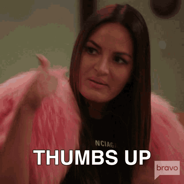 a woman in a pink fur coat is giving a thumbs up sign
