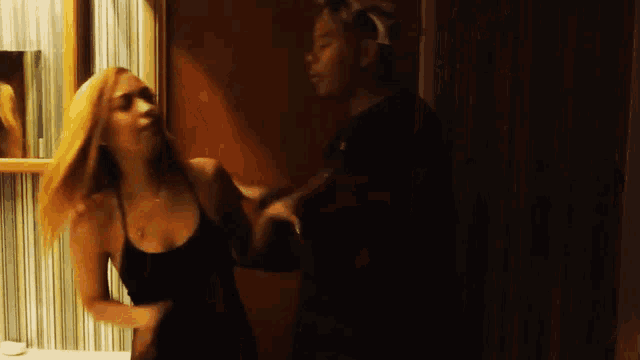a woman in a black dress is dancing with a man in a black shirt