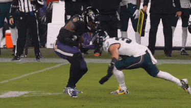 a football player wearing a ravens jersey runs with the ball