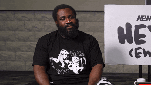 a man sitting in front of a sign that says aew he 's crew