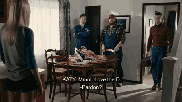 a woman stands in front of a dining room table with two men and says katy mmmm love the d.