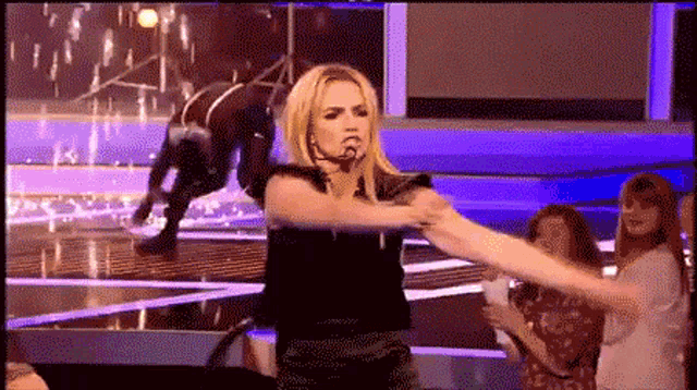 a woman is holding another woman 's arm while standing on a stage