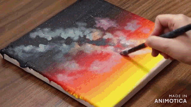 a person is painting a sunset on a canvas with a brush .