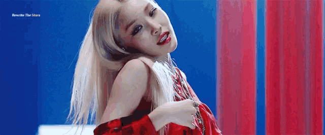 a woman with blonde hair and red lips is wearing a red dress and a red and blue background .