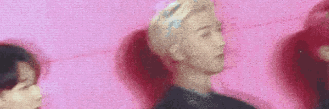a blurry picture of two people standing next to each other against a pink wall .