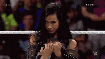 a woman is standing in a wrestling ring holding a pair of gloves .