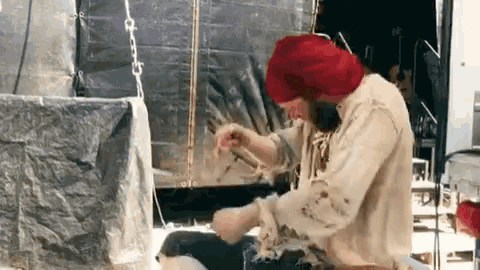 a man wearing a red hat is cutting something with a knife