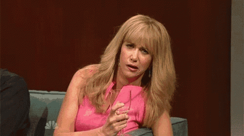 a blonde woman is sitting on a couch holding a glass of wine .