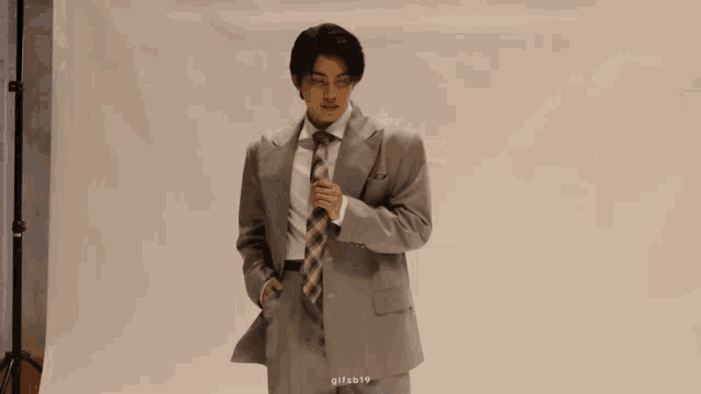 a man in a suit and tie is standing in front of a white backdrop
