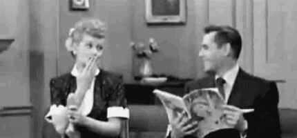 a black and white photo of a man and a woman sitting on a couch .