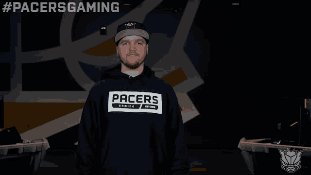 a man wearing a pacers hoodie stands in front of a computer
