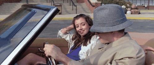 a man wearing a hat is driving a car with a woman in the back seat