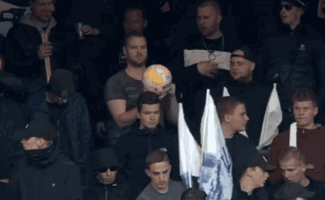 a man holding a soccer ball in a crowd of people with one man wearing a shirt that says ' abercrombie '
