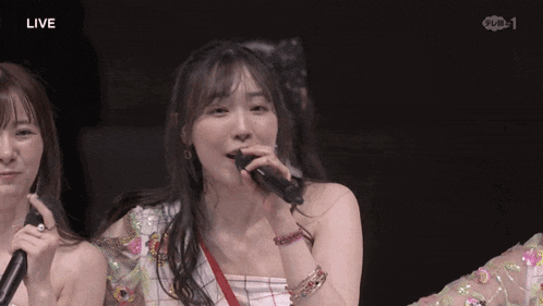 a woman singing into a microphone with the word live on the bottom right