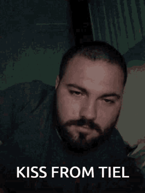 a man with a beard is covering his mouth with his hand with the words kiss from tiel written below him