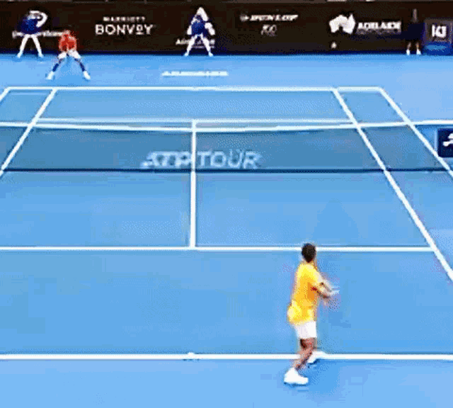 two tennis players are playing on a court with a net that says atptour