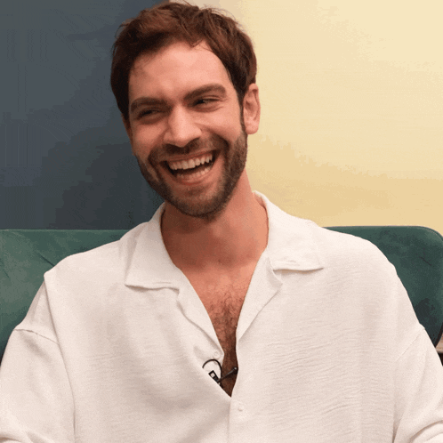 a man wearing a white shirt is laughing with his mouth open