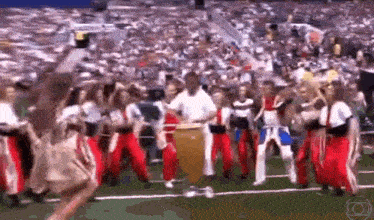 a group of people are dancing and playing drums on a field .