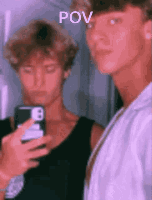 two young men are taking a selfie with their cell phones and the words pov are on the bottom of the image .