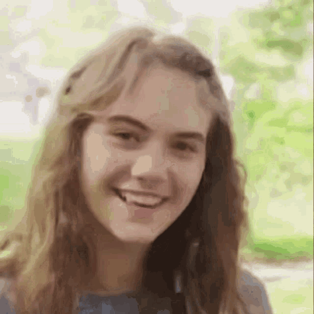 a girl with long hair is smiling for the camera .