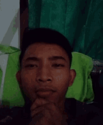 a man is making a funny face while laying on a green pillow