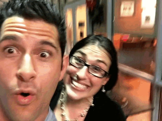 a man and a woman are posing for a picture and the woman has glasses on