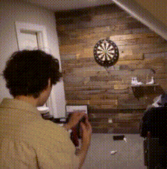 a man is taking a picture of a dart board on a wooden wall