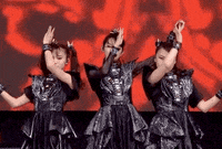 three women in black dresses are dancing on a stage .
