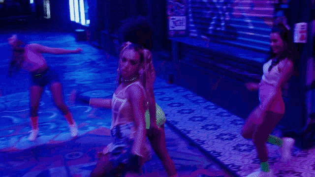 a group of women are dancing in a dark room with a sign that says ' icon ' in the background