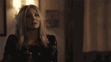 a woman is sitting at a table in a dark room looking at something .