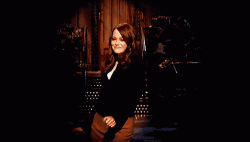 a woman in a black sweater and brown pants is dancing on stage