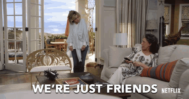 two women sitting on a couch with the words " we 're just friends " written on the bottom