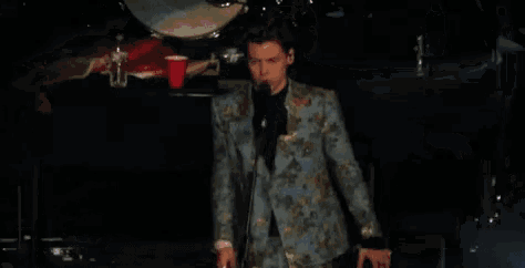 a man in a suit is dancing on stage in front of a microphone .