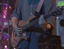 a man is playing a bass guitar in front of a green sign that says ' exit '