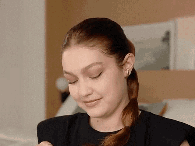 a close up of a woman 's face with her eyes closed and a ponytail .