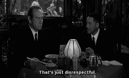 two men are sitting at a table in a restaurant with chopsticks .