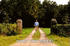 a man is walking down a dirt road with the words wait for meee written on the side .