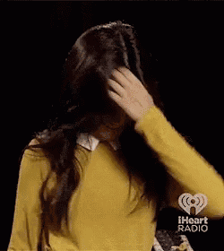 a woman in a yellow sweater is touching her head .