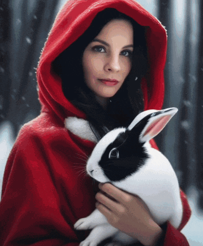 a woman in a red cape is holding a white and black rabbit