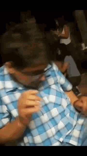 a man in a plaid shirt is holding a glass