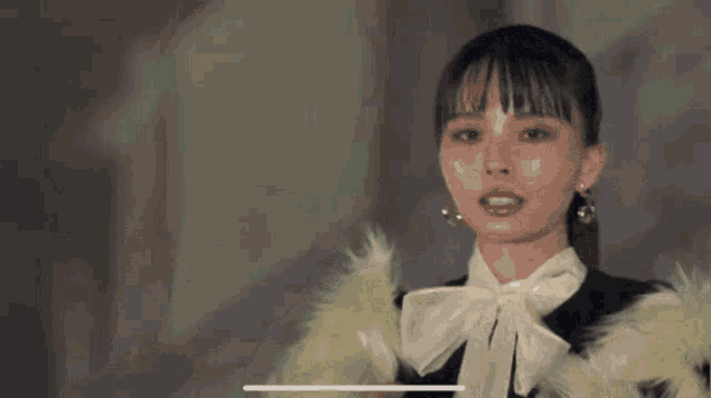 a woman wearing a fur coat and a bow tie is looking at the camera .