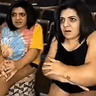 two women are sitting next to each other with their arms crossed in a room .