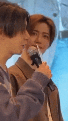 a man is holding a microphone and talking to another man .