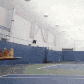 an indoor tennis court with a table in the foreground and the word ny on the wall
