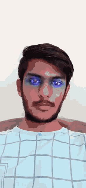 a man with blue eyes and a beard is wearing a blue and white checkered shirt